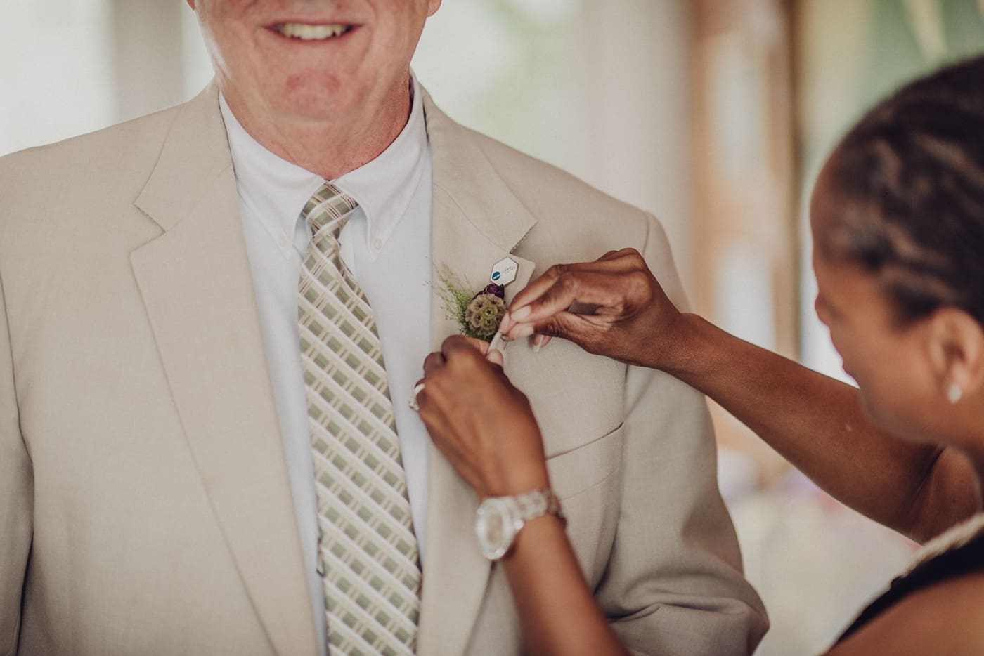 Wedding planner pinning boutonniere on groom