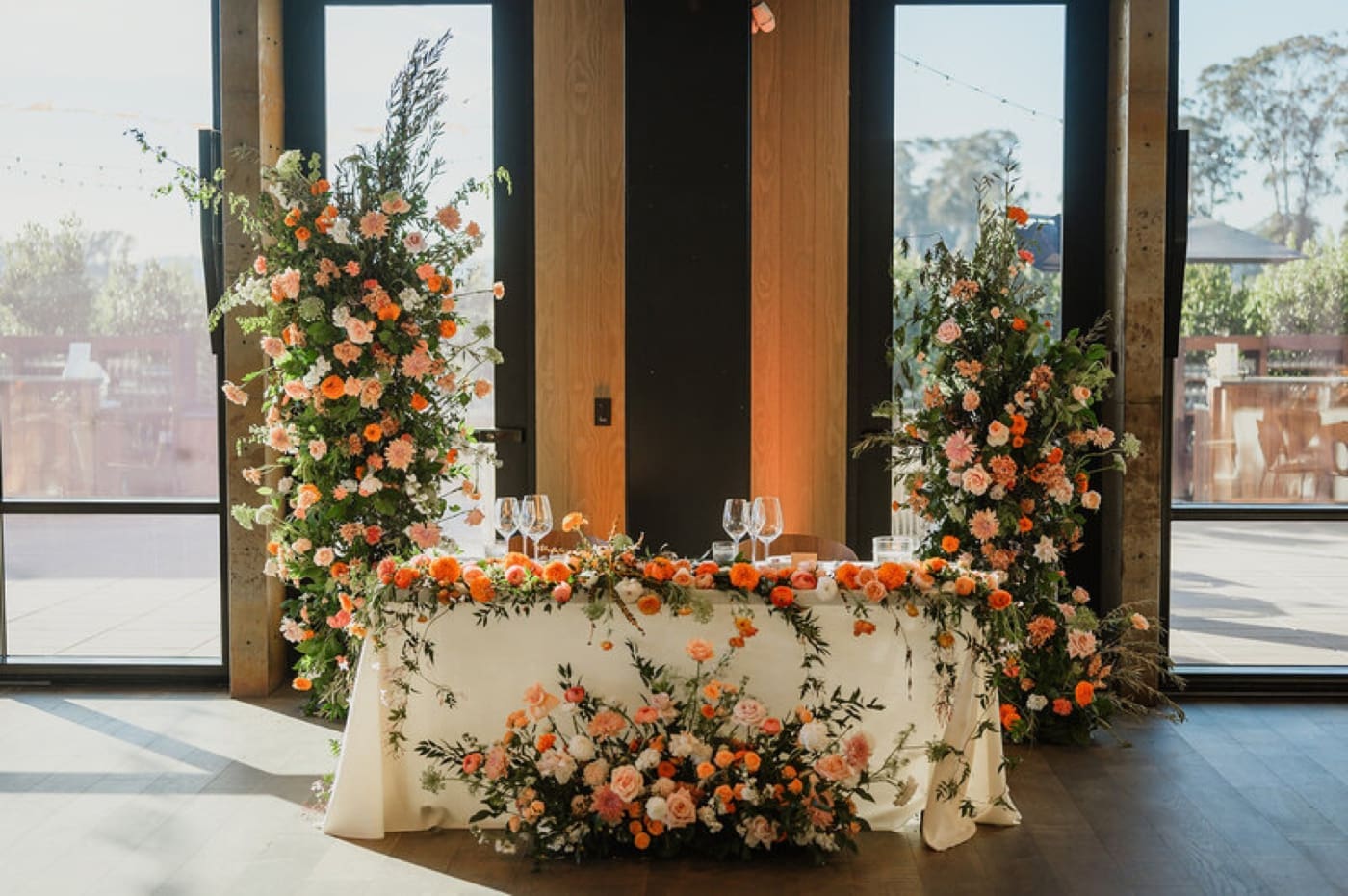 Sweetheart table decorated with orange and peach flowers for a Central California wedding
