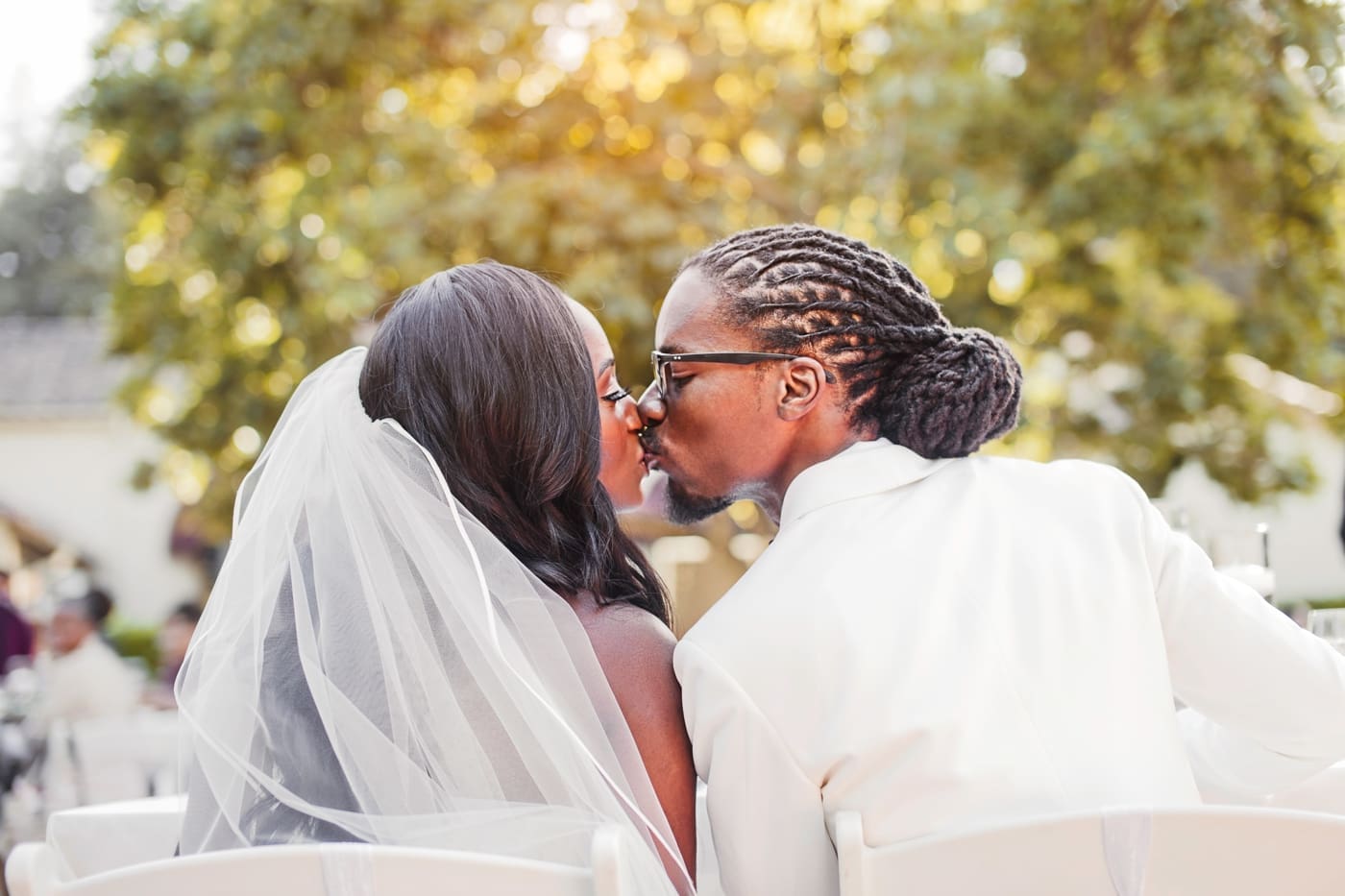 Bride and groom kissing in front of trees