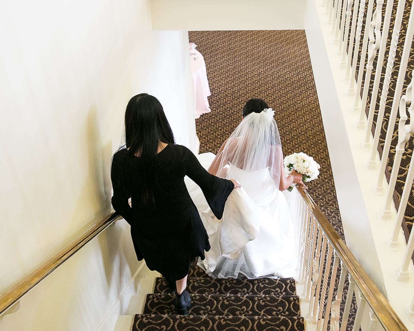 Wedding planner helping bride walk down stairs